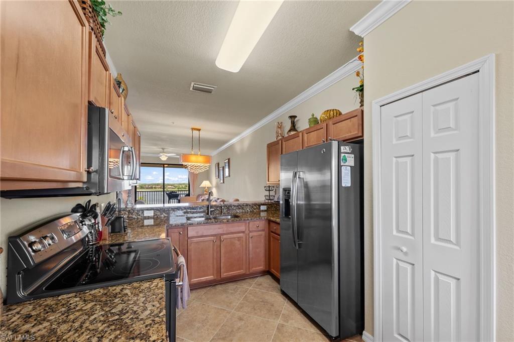 Kitchen featuring wood cabinetry, stainless steel appliances, granite countertops, and tile flooring