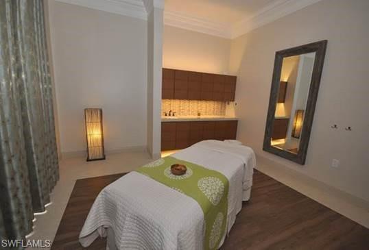 Interior space featuring wood-finish flooring, crown molding, and a built-in vanity with upper and lower cabinetry