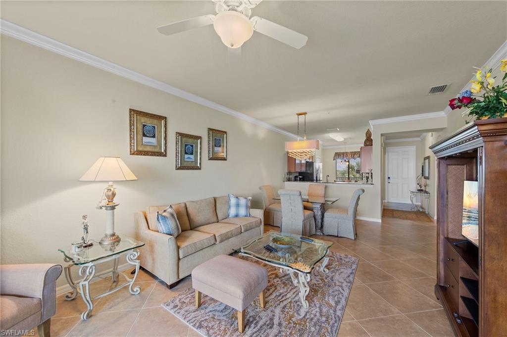 Open-concept living space featuring neutral tone wall paint, crown molding, and diagonal tile flooring