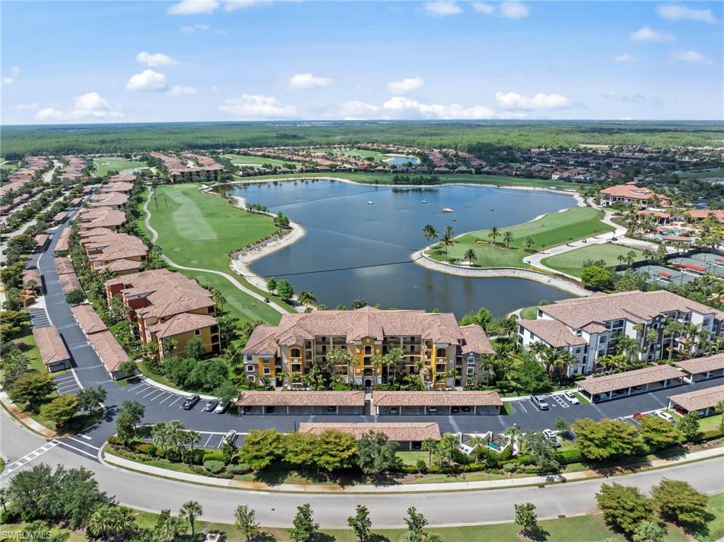 Expansive residential community featuring a large central lake, golf course, multiple multi-story buildings, covered parking structures, and extensive landscaping