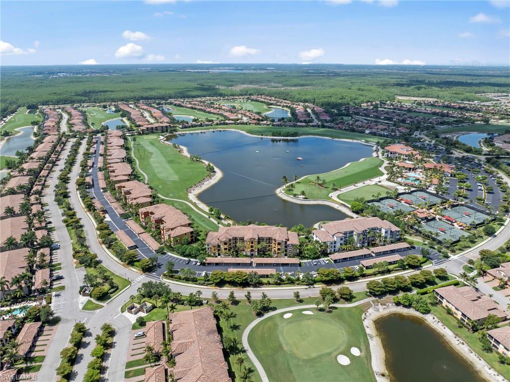 Expansive residential community featuring a central lake, golf course, multiple tennis courts, and numerous multi-story buildings with tile roofs