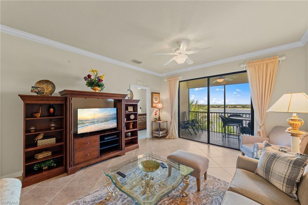Expansive living area featuring large format tile flooring, crown molding, and a ceiling fan