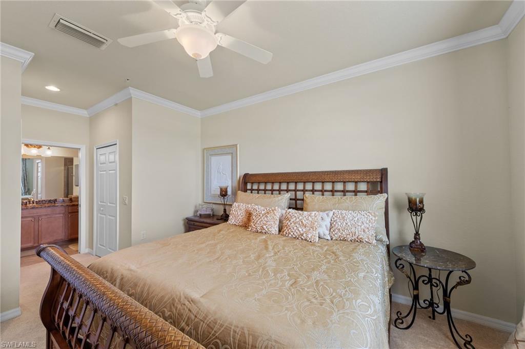 Neutral toned walls and carpeting, crown molding, and a ceiling fan with light fixture