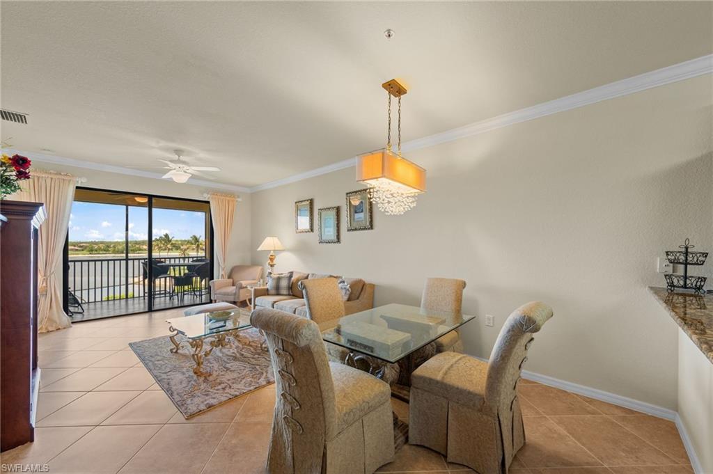 Open-concept living and dining area featuring tile flooring, crown molding, and a chandelier with crystal accents