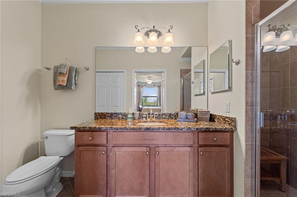 Bathroom vanity featuring a polished stone countertop, wood-finish cabinetry, and an integrated sink with a chrome faucet