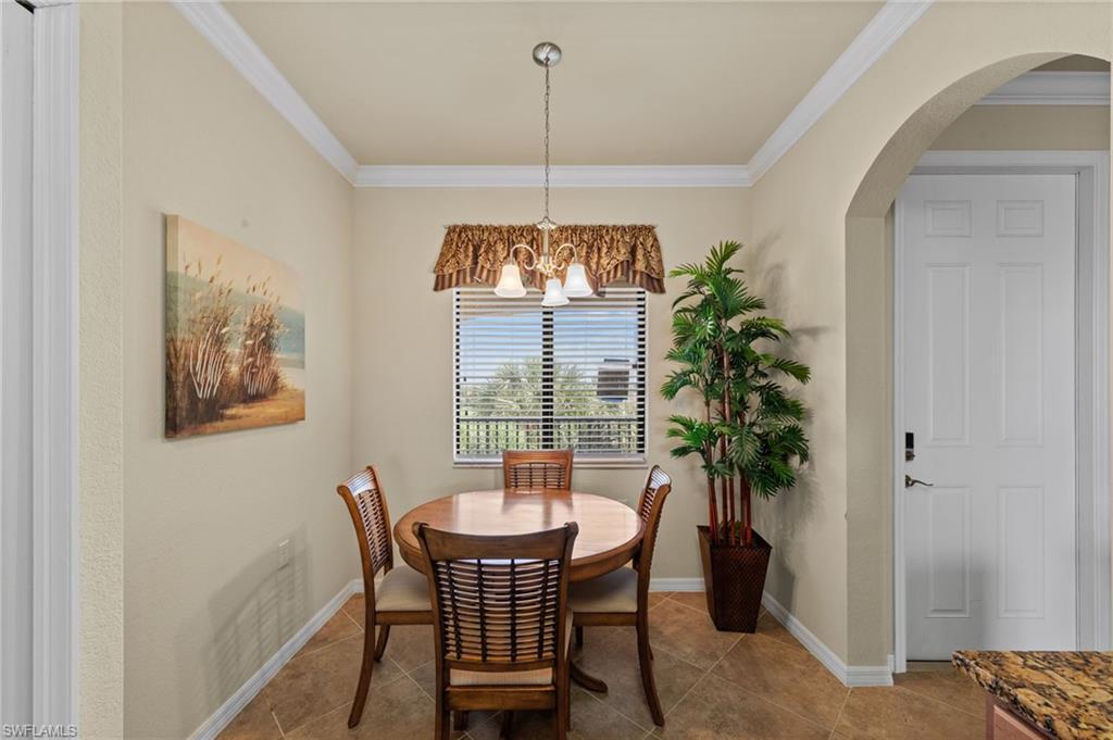 Dining space featuring tile flooring, crown molding, a window with horizontal blinds, and an arched entry