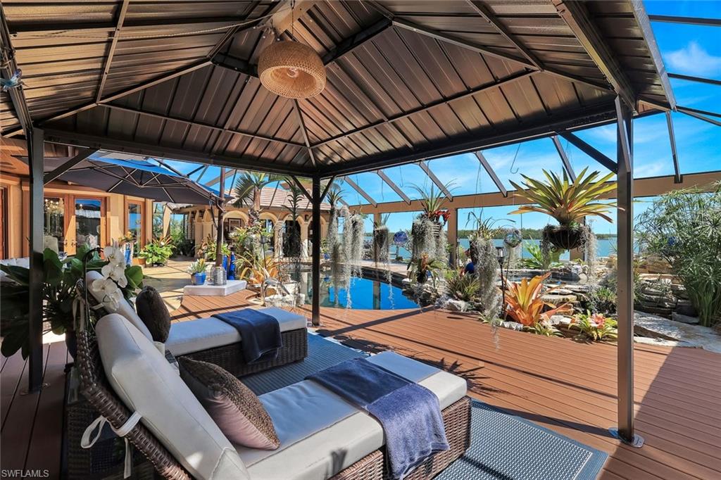 Screened outdoor living area featuring a covered gazebo, composite decking, and a built-in pool with a waterfall feature