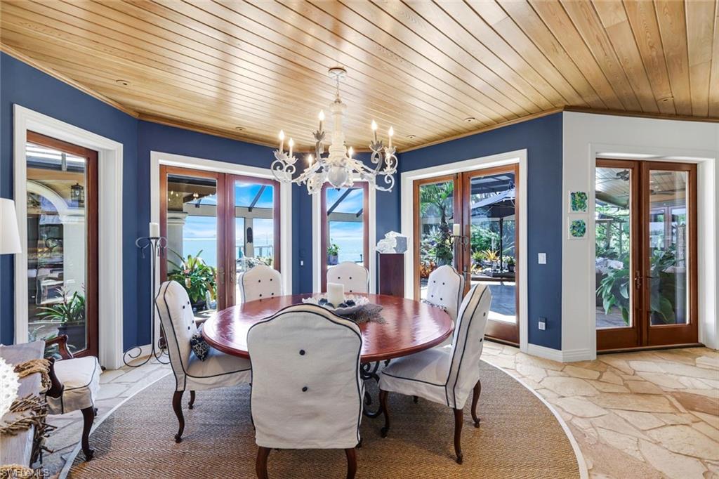 Dining area featuring rich blue walls, a wood-plank ceiling, and flagstone flooring with a natural fiber area rug