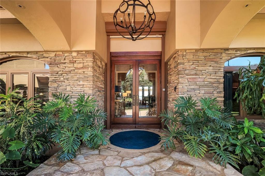 Stacked stone facade with arched entryways and a wood-frame double-door entrance featuring glass panels