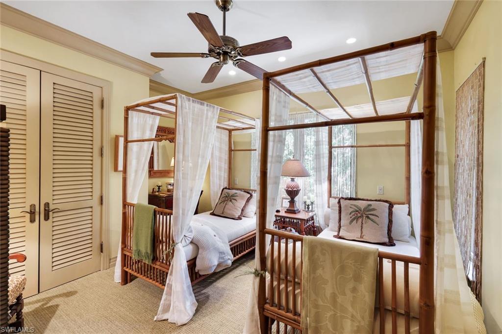 Room featuring two four-poster beds with sheer canopies, louvered double doors, a ceiling fan, and crown molding