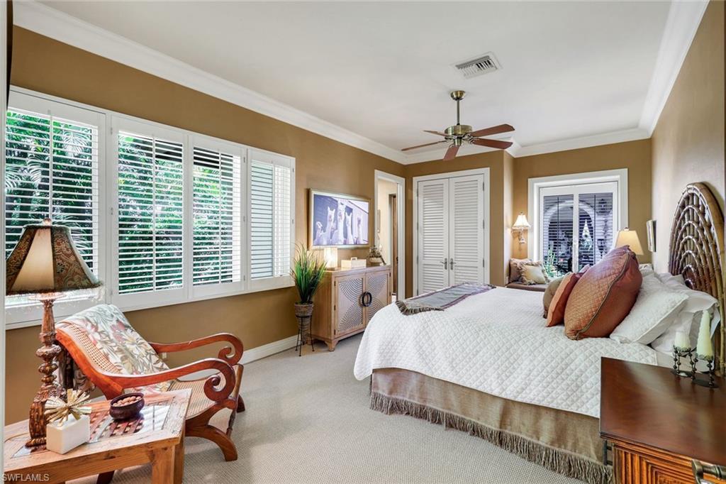Spacious bedroom featuring light-colored carpet flooring, crown molding, and a ceiling fan