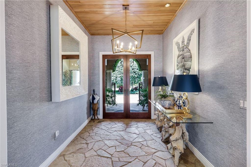 Entryway featuring a natural wood plank ceiling, a geometric chandelier, and flagstone flooring