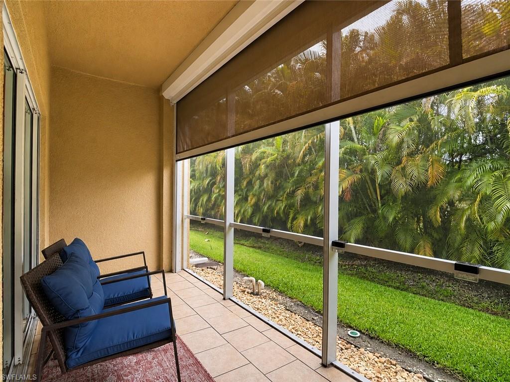 Screened lanai featuring tile flooring, textured stucco walls, and a retractable Hurricane Shade