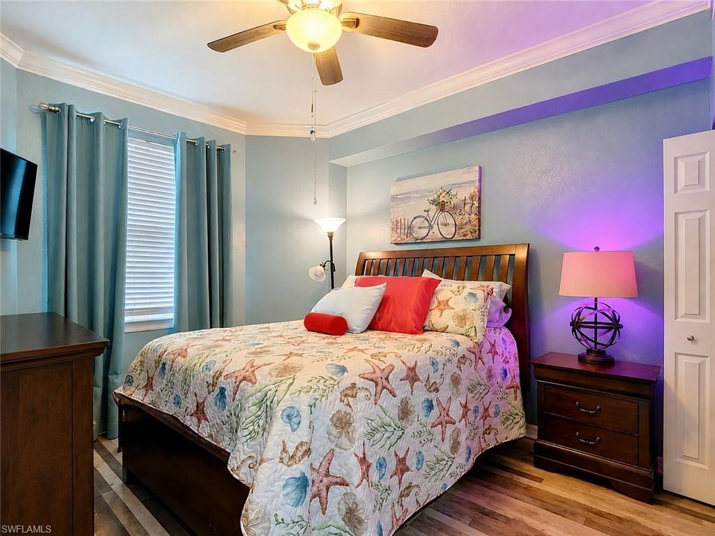 Bedroom featuring wood-finish flooring, a ceiling fan, a window with blinds, and crown molding