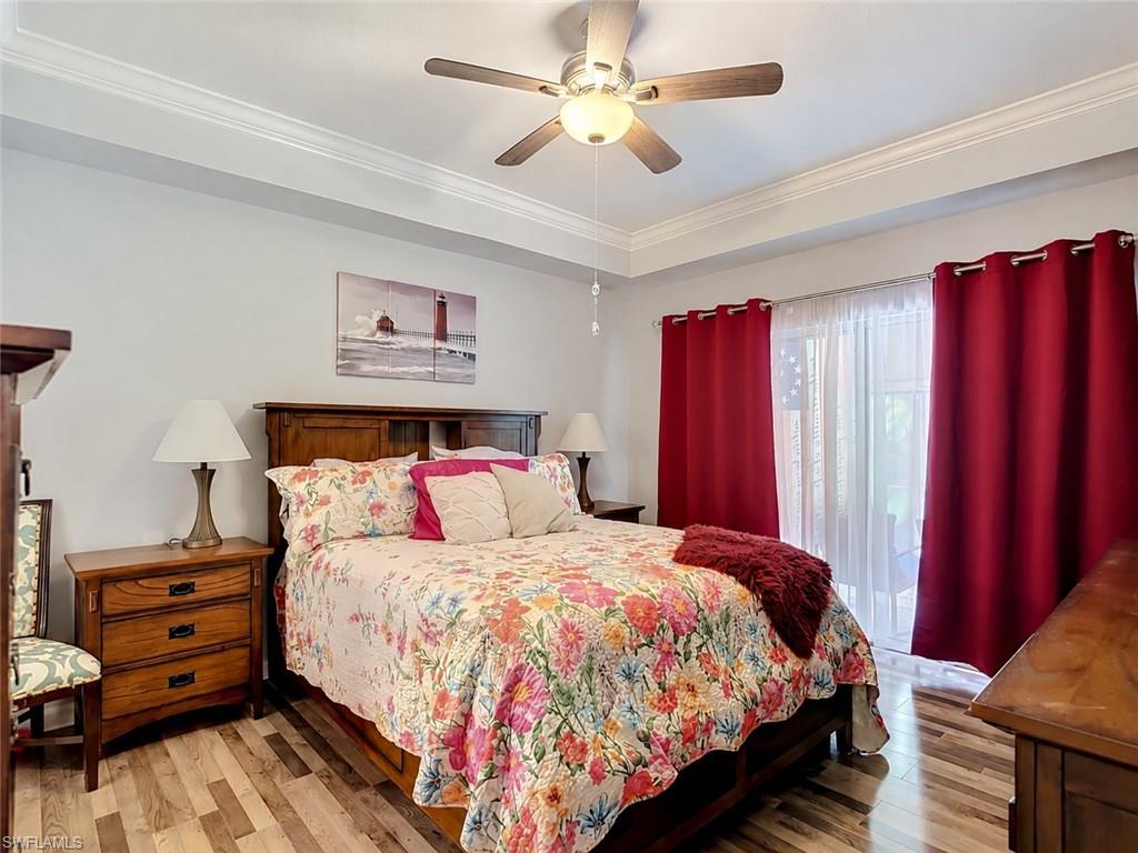 Bedroom featuring wood-finish flooring, a tray ceiling with crown molding, and a ceiling fan, Walk In Closet
