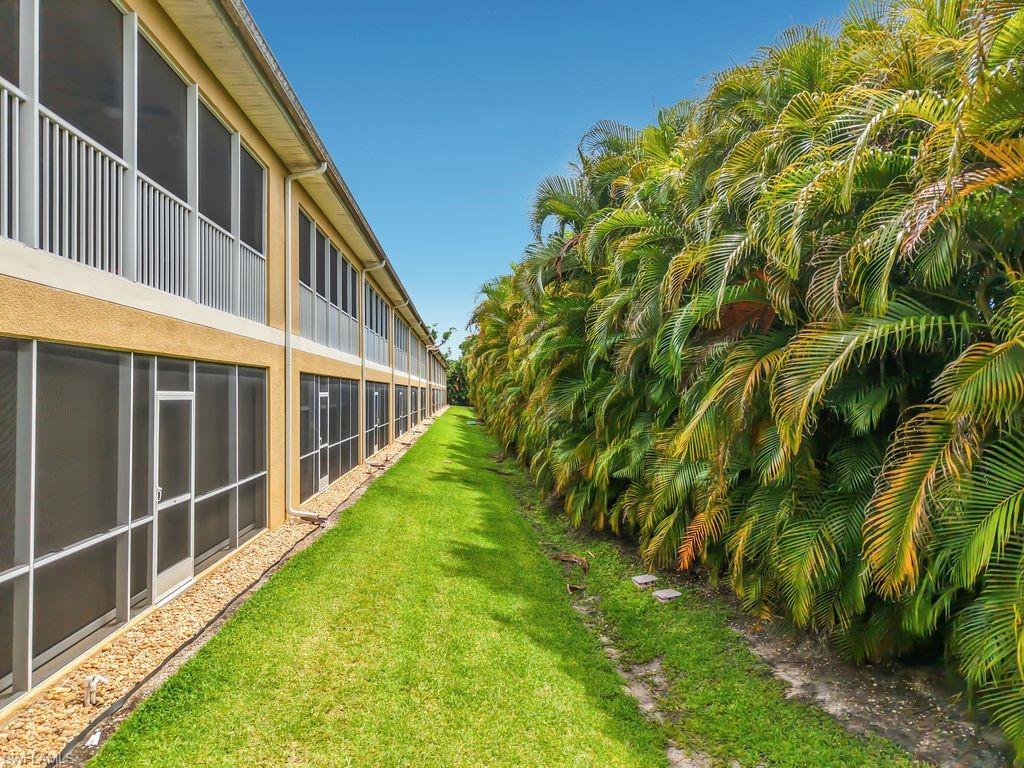 Exterior of a multi-story building featuring screened ground-floor patios and upper-level screened balconies