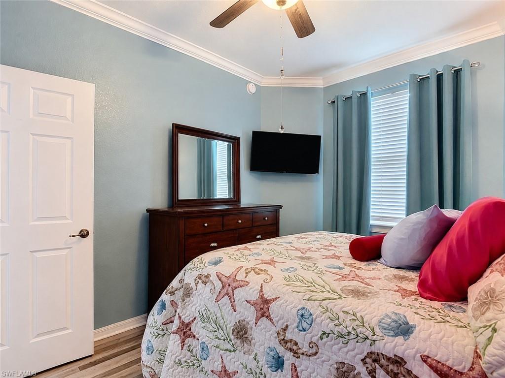 Bedroom with crown molding, wood-finish flooring, and a ceiling fan