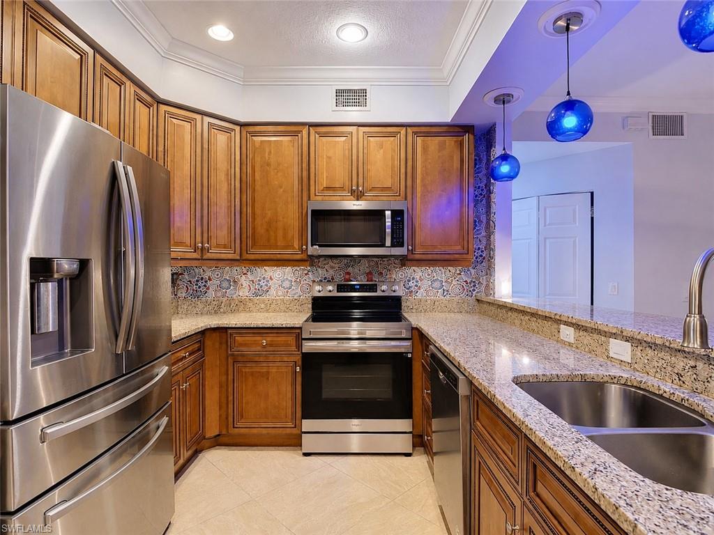 Kitchen featuring rich wood cabinetry, stainless steel appliances, granite countertops, and a decorative tile backsplash
