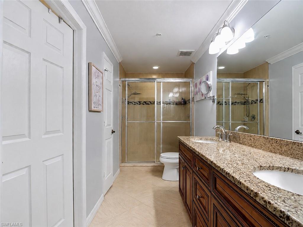 Bathroom featuring a dual vanity with a granite-style countertop, undermount sinks, Walk In shower, and Walk In Closet Off of Bathroom