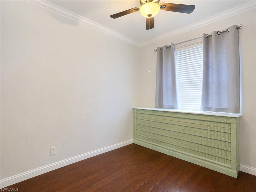Room featuring wood-finish flooring, crown molding, and baseboards