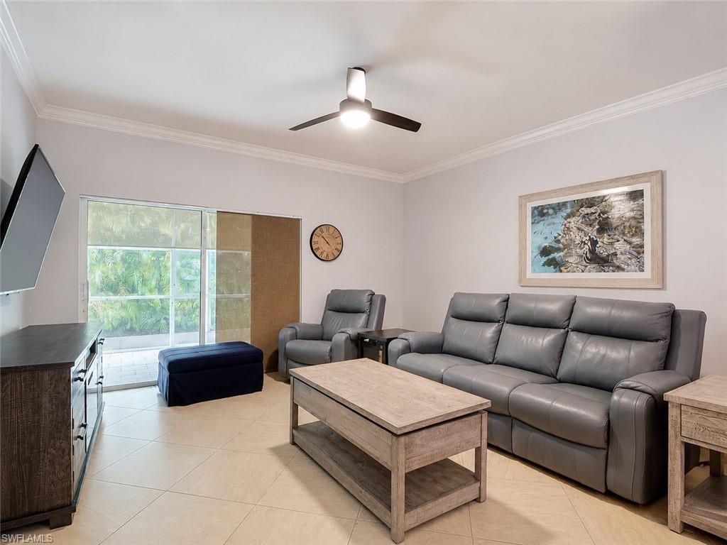 Living area featuring tile flooring, sliding glass doors, crown molding, and a ceiling fan with integrated lighting