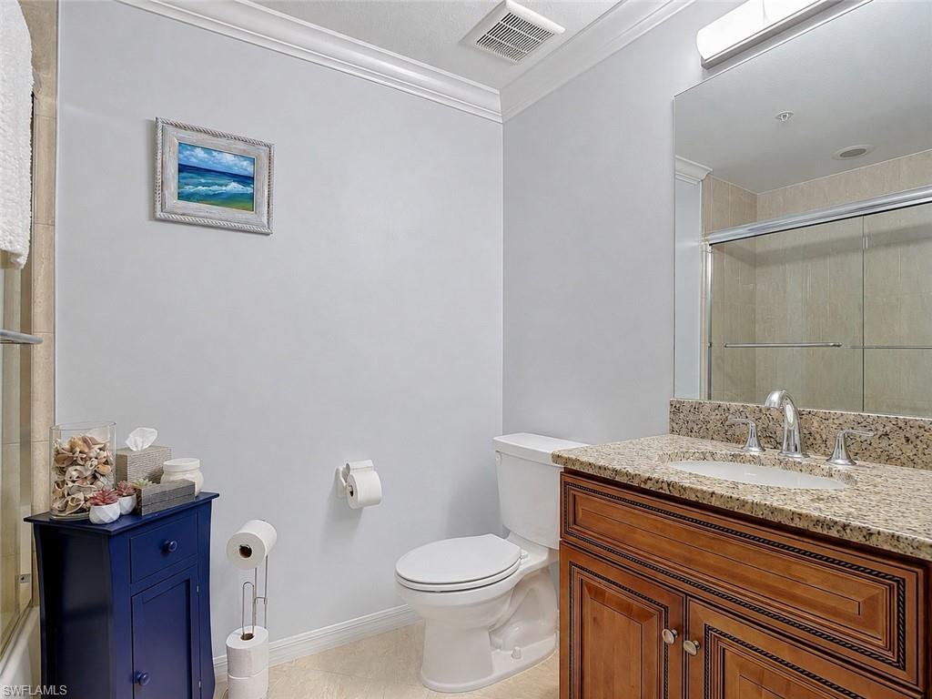 Bathroom featuring a wood-finish vanity with a granite countertop, undermount sink, and chrome fixtures