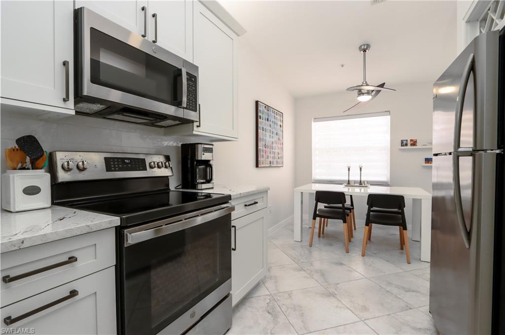 Kitchen with stainless steel appliances, light marble finish flooring, light stone countertops, and white cabinets