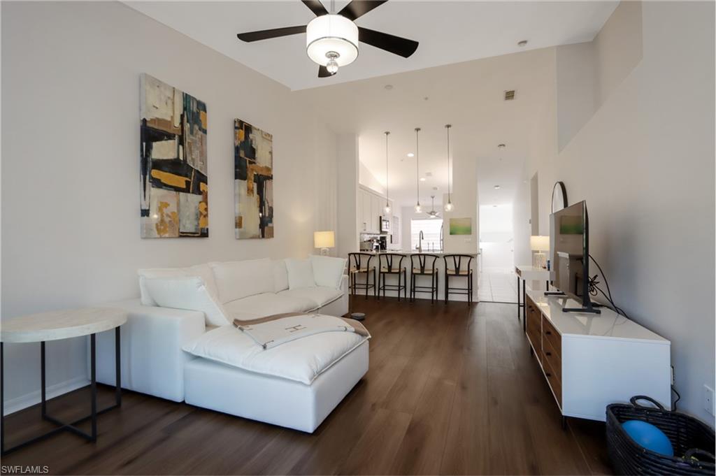 Living room with ceiling fan and dark wood-style flooring