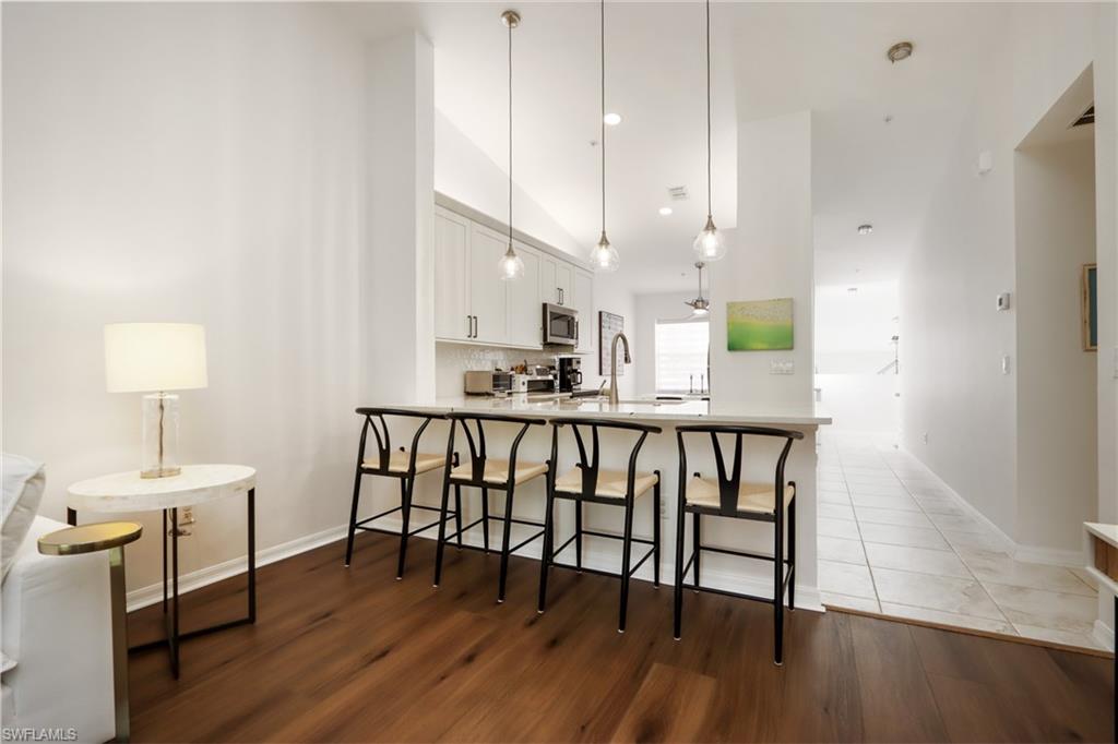 Kitchen with stainless steel microwave, white cabinets, a kitchen bar, a peninsula, and light wood-style floors