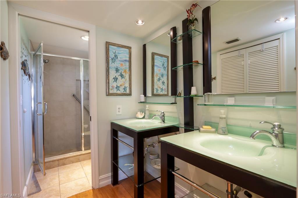 Full bath featuring two vanities, a stall shower, and recessed lighting