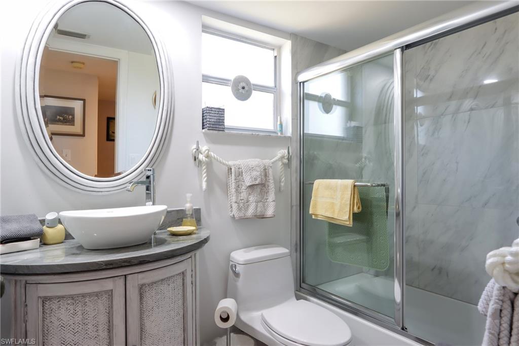Bathroom with vanity and combined bath / shower with glass door