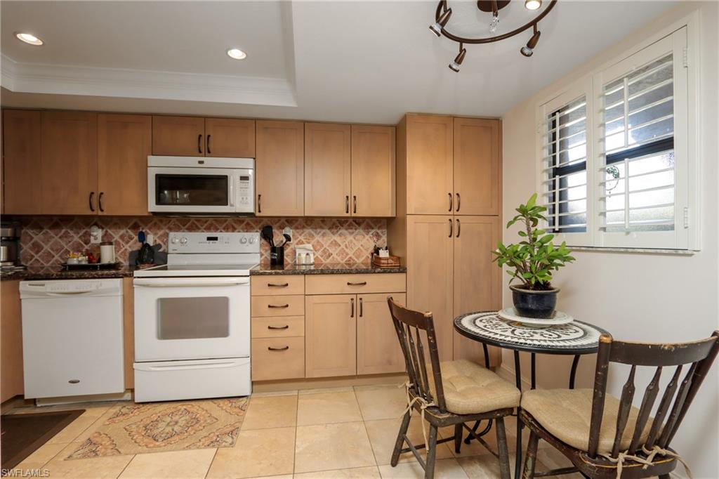 Kitchen with white appliances, decorative backsplash, a tray ceiling, recessed lighting, and light tile patterned flooring