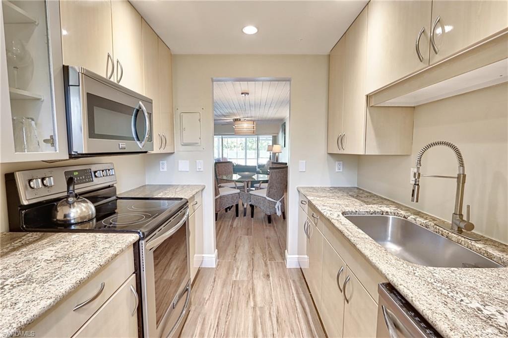 Kitchen featuring sink, appliances with stainless steel finishes, light hardwood / wood-style flooring, and light stone counters