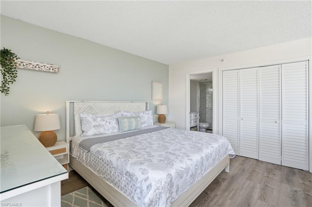 Bedroom featuring wood-finish flooring and a light-toned accent wall - Virtually Edited Image