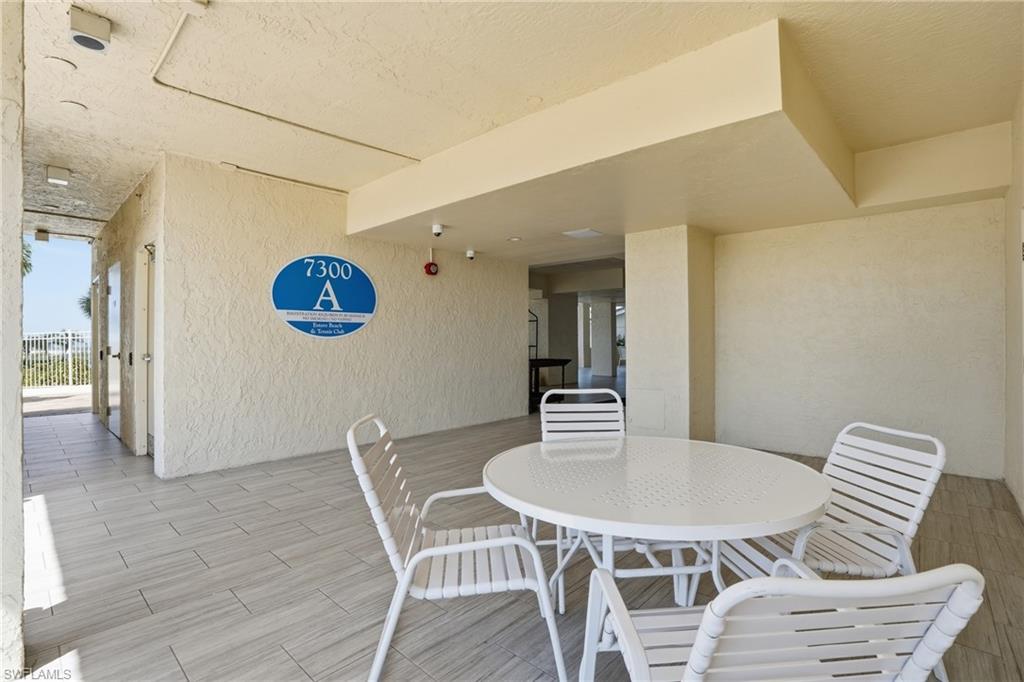 Covered outdoor patio area featuring light-toned stucco walls and plank-style tile flooring - Virtually Edited Image