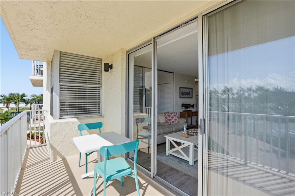 Outdoor balcony featuring a textured wall finish, white metal railing, and sliding glass doors - Virtually Edited Image