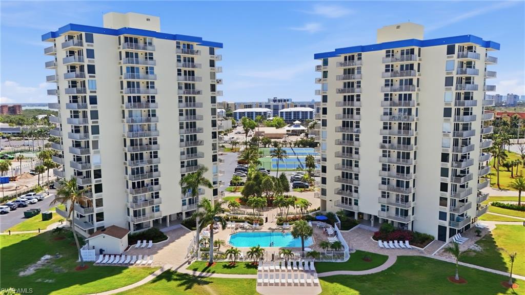 Twin high-rise buildings featuring private balconies, an outdoor swimming pool, a tennis court, and surrounding green spaces - Virtually Edited Image