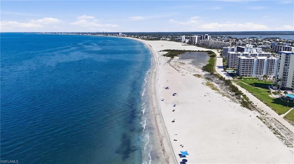 Expansive coastline featuring a broad sandy beach, clear blue ocean waters, and a distinct shoreline - Virtually Edited Image