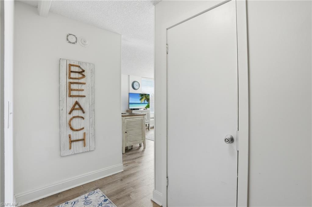 Entryway featuring light wood-finish flooring, white baseboards, and a white interior door with a chrome knob - Virtually Edited Image