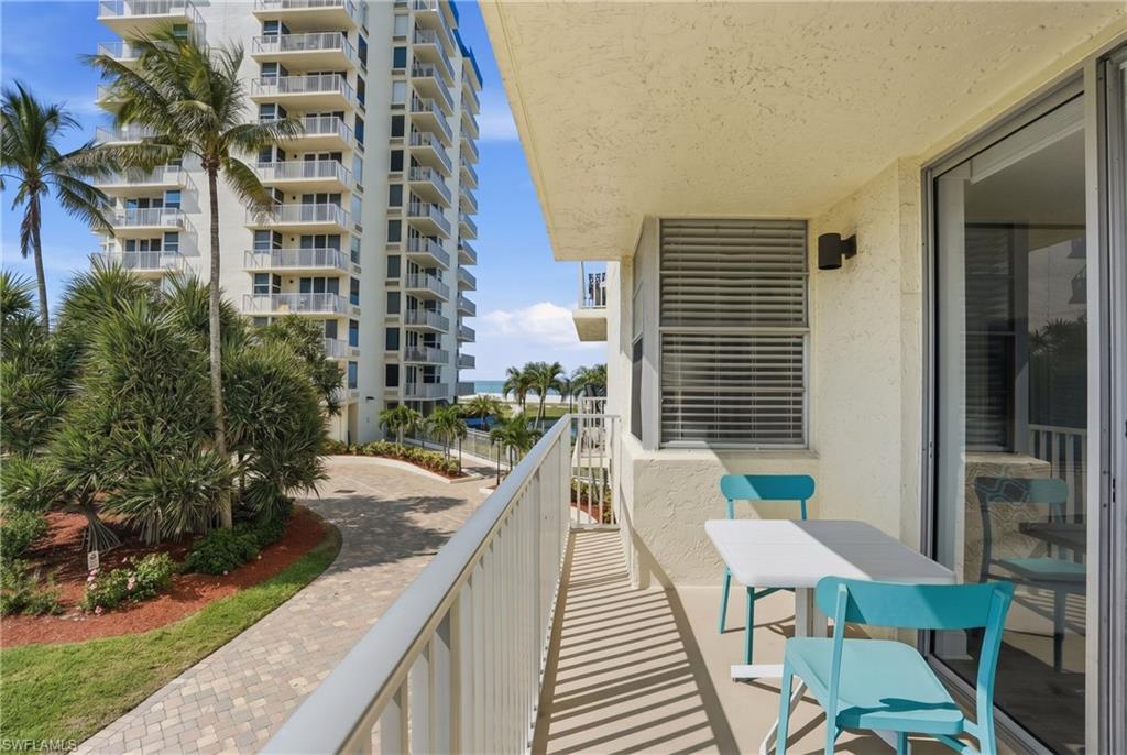 Outdoor balcony featuring a stucco exterior, sliding glass doors, white railings, and an exterior wall light - Virtually Edited Image