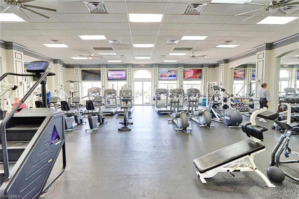 Workout area featuring a drop ceiling, ornamental molding, and ceiling fan