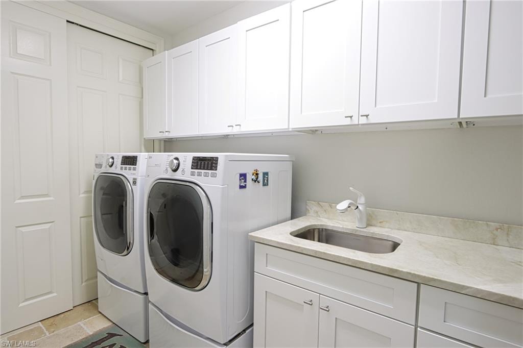 Laundry area featuring sink, cabinets, washer and dryer, and light tile patterned floors