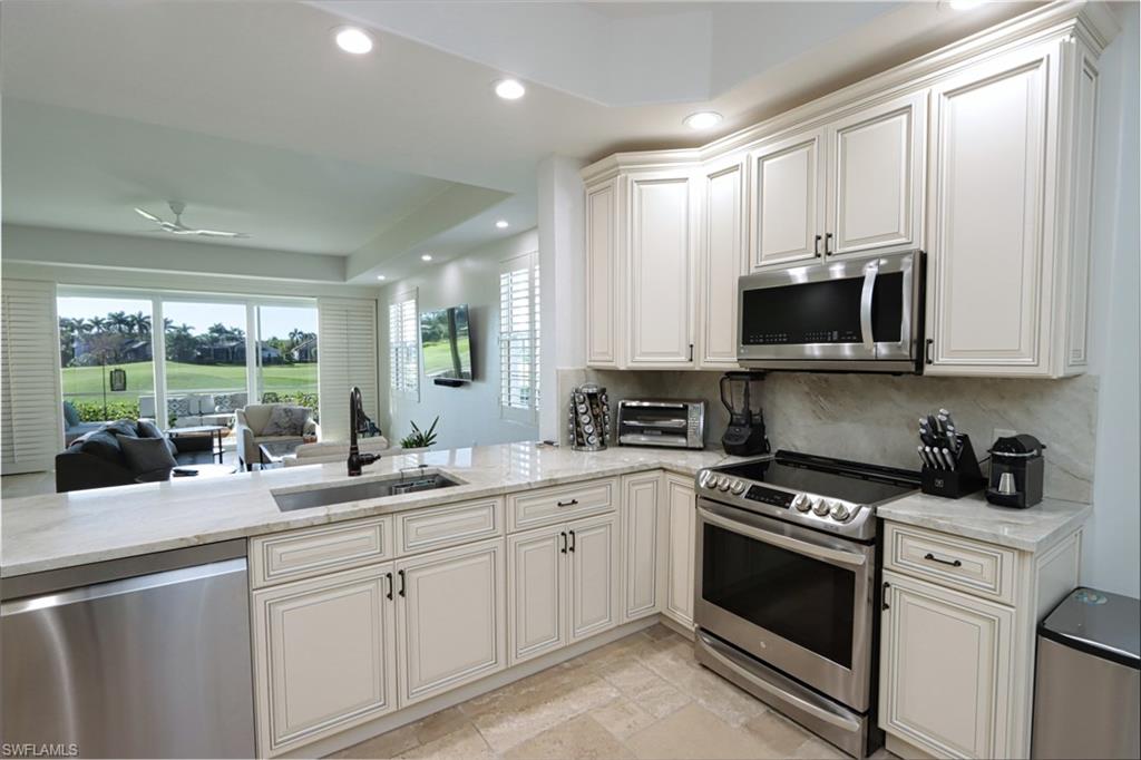 Kitchen with tasteful backsplash, light tile patterned floors, light stone counters, appliances with stainless steel finishes, and sink