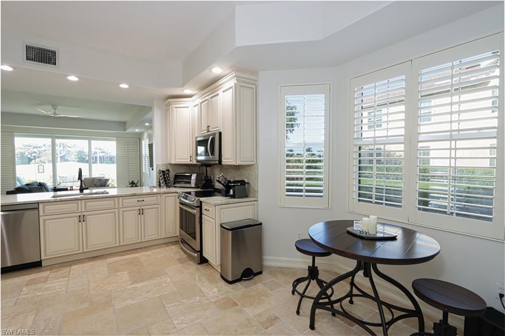 Kitchen featuring tasteful backsplash, a tray ceiling, sink, appliances with stainless steel finishes, and light tile patterned floors