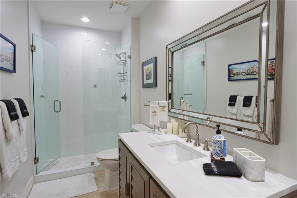 Bathroom with vanity, walk in shower, tile patterned flooring, and toilet