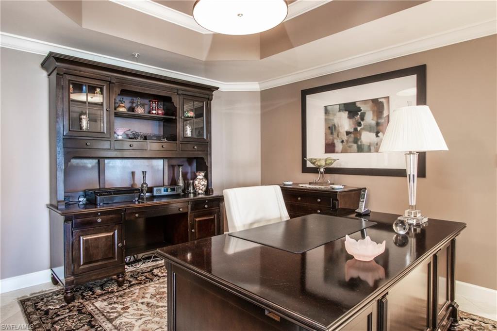 Office area with ornamental molding, light tile floors, and a raised ceiling