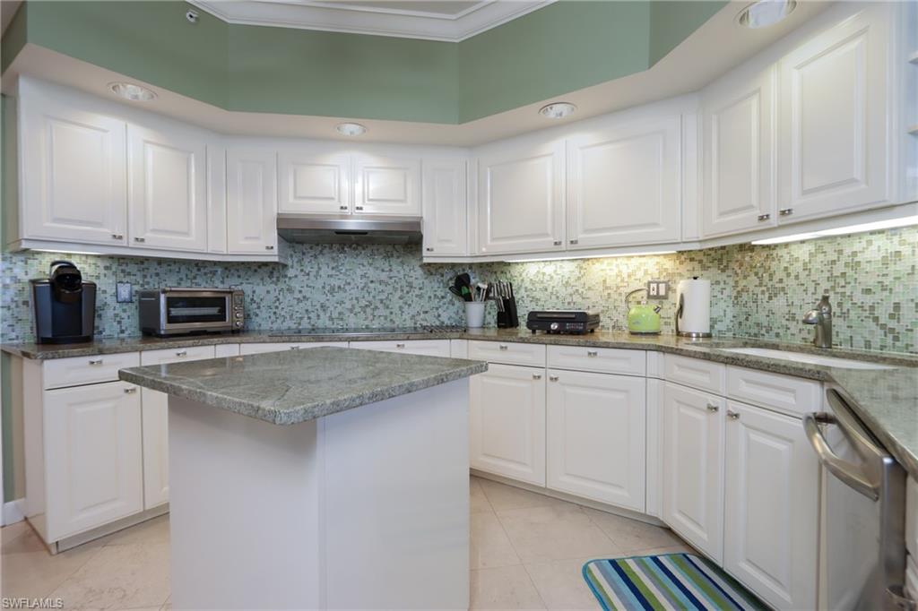 Kitchen with tasteful backsplash, dishwasher, a kitchen island, light tile floors, and white cabinets