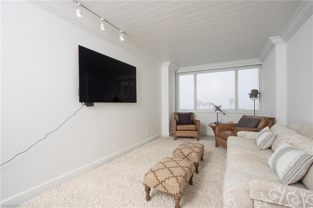 Carpeted living room featuring ornamental molding, rail lighting, and baseboards