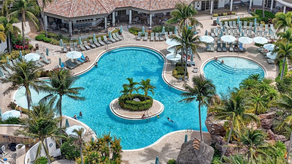 Players Club and Spa Resort Pool featuring a freeform main pool with a central island, an additional curvilinear pool area, and a dedicated zero-entry area. Also highlighting the club house outdoor dining areas