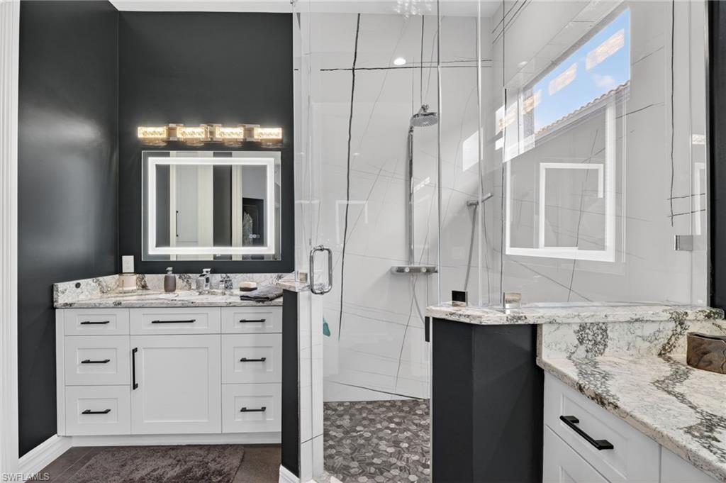 Primary Oasis featuring a frameless glass shower enclosure, a white shaker vanity with illuminated LED heated, anti-fog, dimmable, tone adjustable mirrors